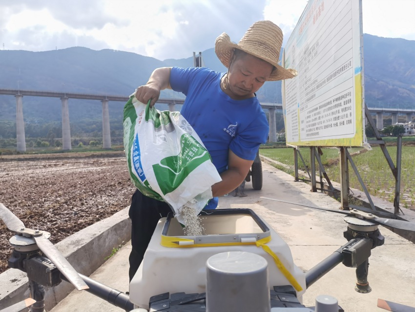 村民正在向無(wú)人機(jī)添裝肥料。德昌縣委宣傳部供圖
