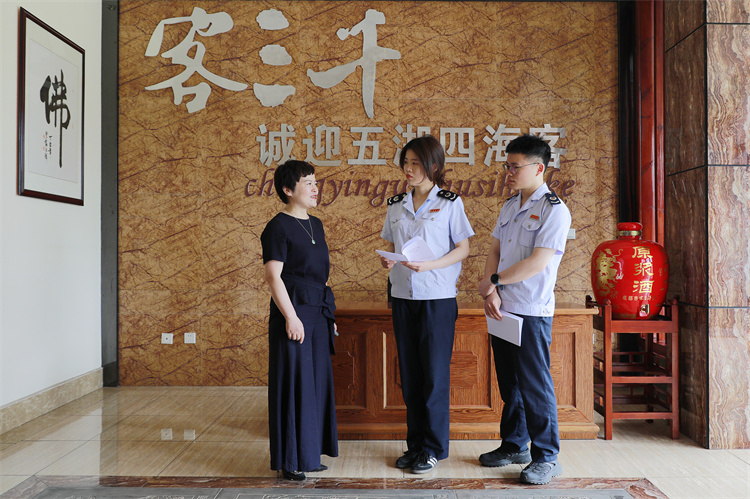 成都稅務(wù)工作人員向客三千酒廠財務(wù)負(fù)責(zé)人講解“銀稅互動”政策，送上《支持制造業(yè)發(fā)展主要稅費(fèi)優(yōu)惠政策指引》。成都市稅務(wù)局供圖