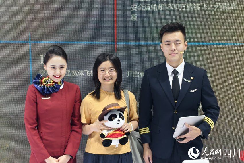 參與互動的參展觀眾在領取禮物后同中國國際航空公司展館工作人員合影。人民網 趙祖樂攝