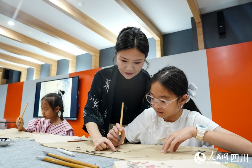 四川大學錦江學院“90后”副教授高子然在眉山市彭山區文化館指導孩子們畫中國畫。人民網 趙祖樂攝