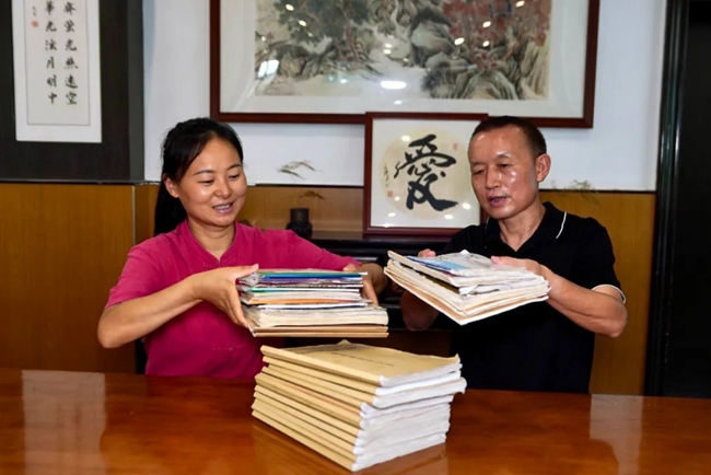 2025年7月30日，王成富和店長李小娟整理8年來免費人員吃飯登記冊。劉婷供圖