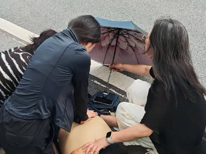 張璐瓊跪在路面上，對老人進行心肺復蘇。達州融媒供圖
