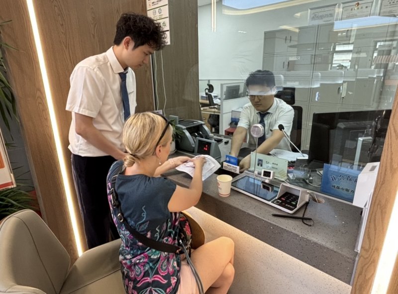 為從波蘭來(lái)成都旅游的游客將100美元兌換成人民幣。唐聰攝
