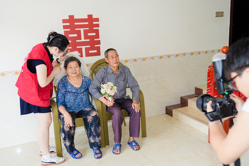 志愿者為金婚夫婦拍攝合照現(xiàn)場。余文攝