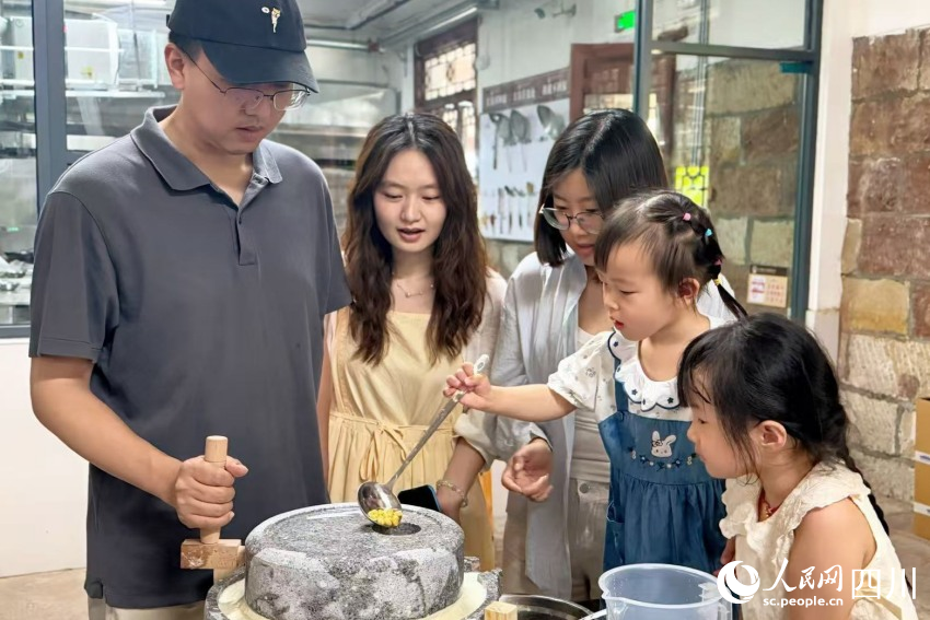 參加研學(xué)的孩子在家長(zhǎng)的陪同下，上手體驗(yàn)先市醬油制作（部分環(huán)節(jié)）。楊藺攝